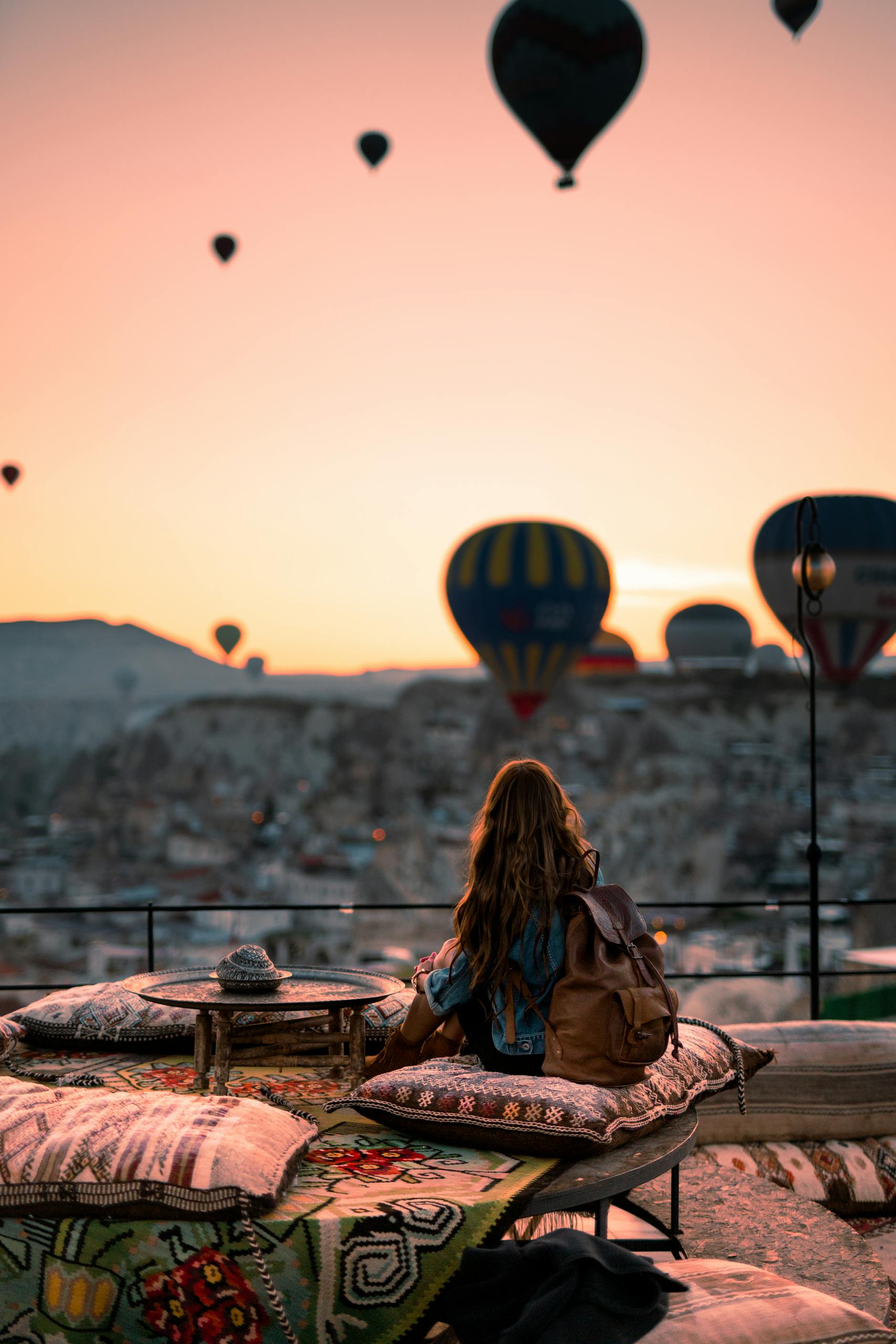 Woman gazing at hot air balloons in Cappadocia at sunrise, Turkey.
