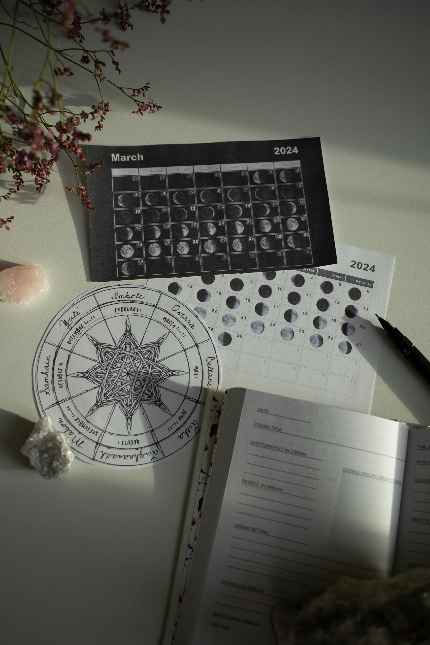 A detailed view of astrology moon phases with a calendar and journal on a white desk.