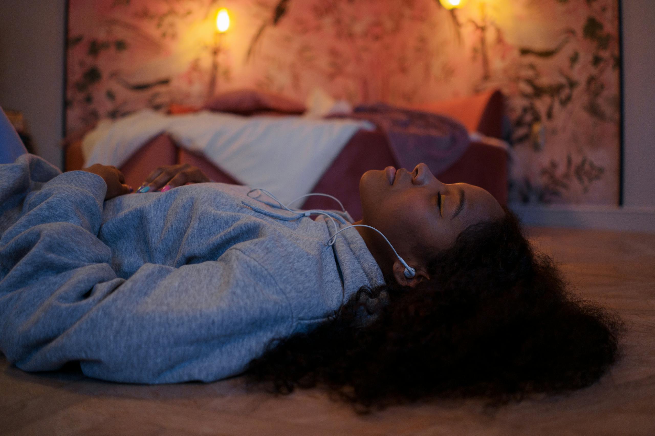 Woman resting indoors, eyes closed, enjoying music in a cozy room.