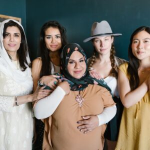 A diverse group of women smiling, showcasing empowerment and unity in traditional and modern clothing.