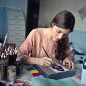 Female artist deeply engaged in painting at her creative studio workspace.